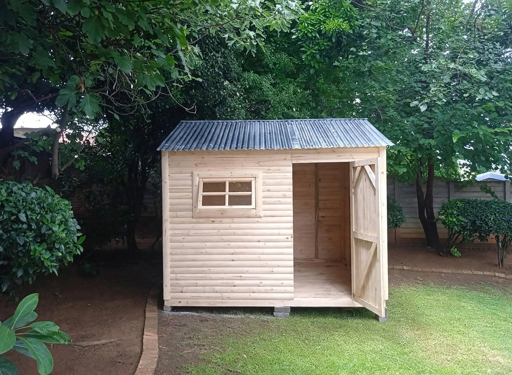 Small light-coloured Wendy house among trees
