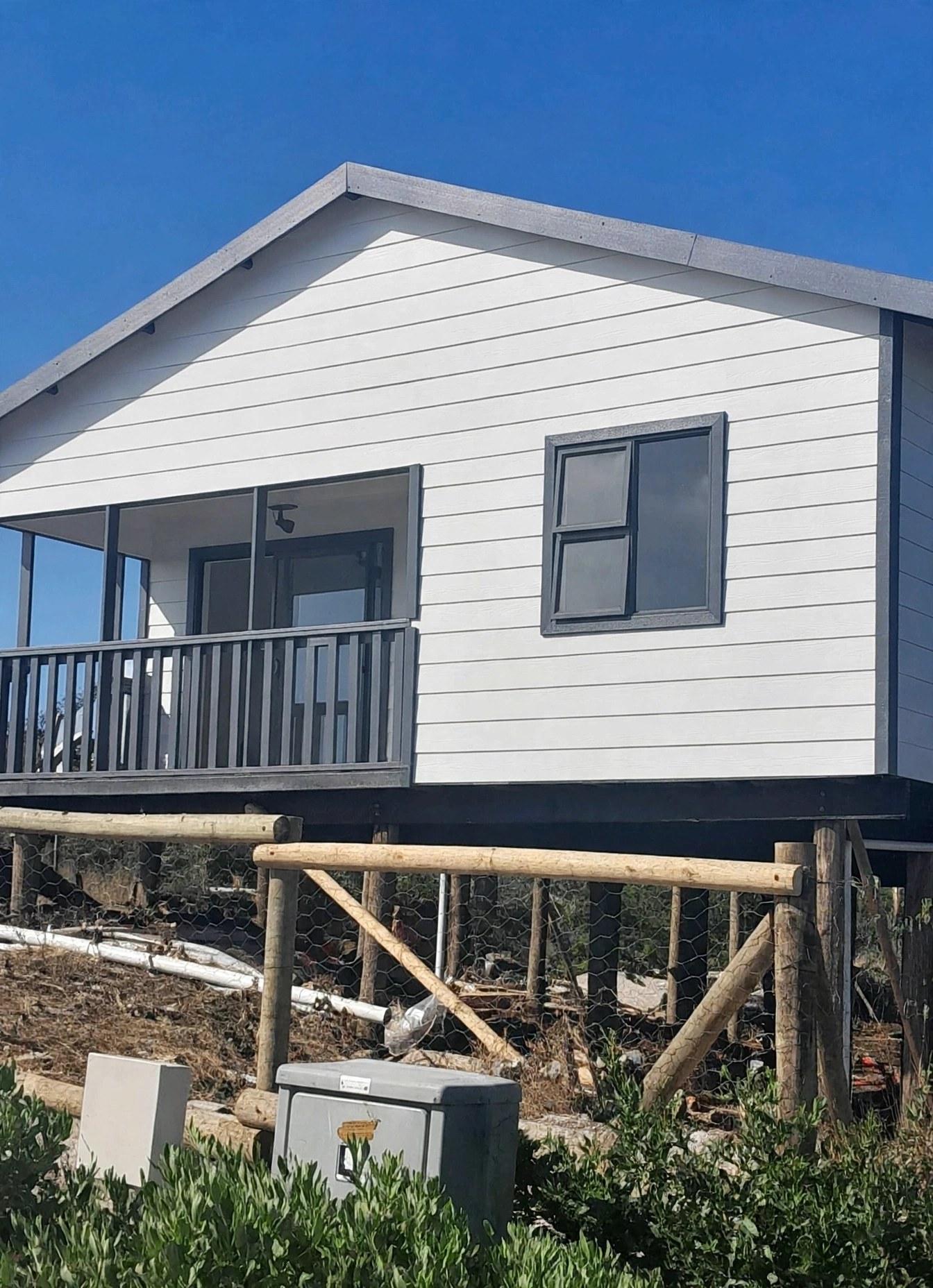 Raised white home with dark balcony railing