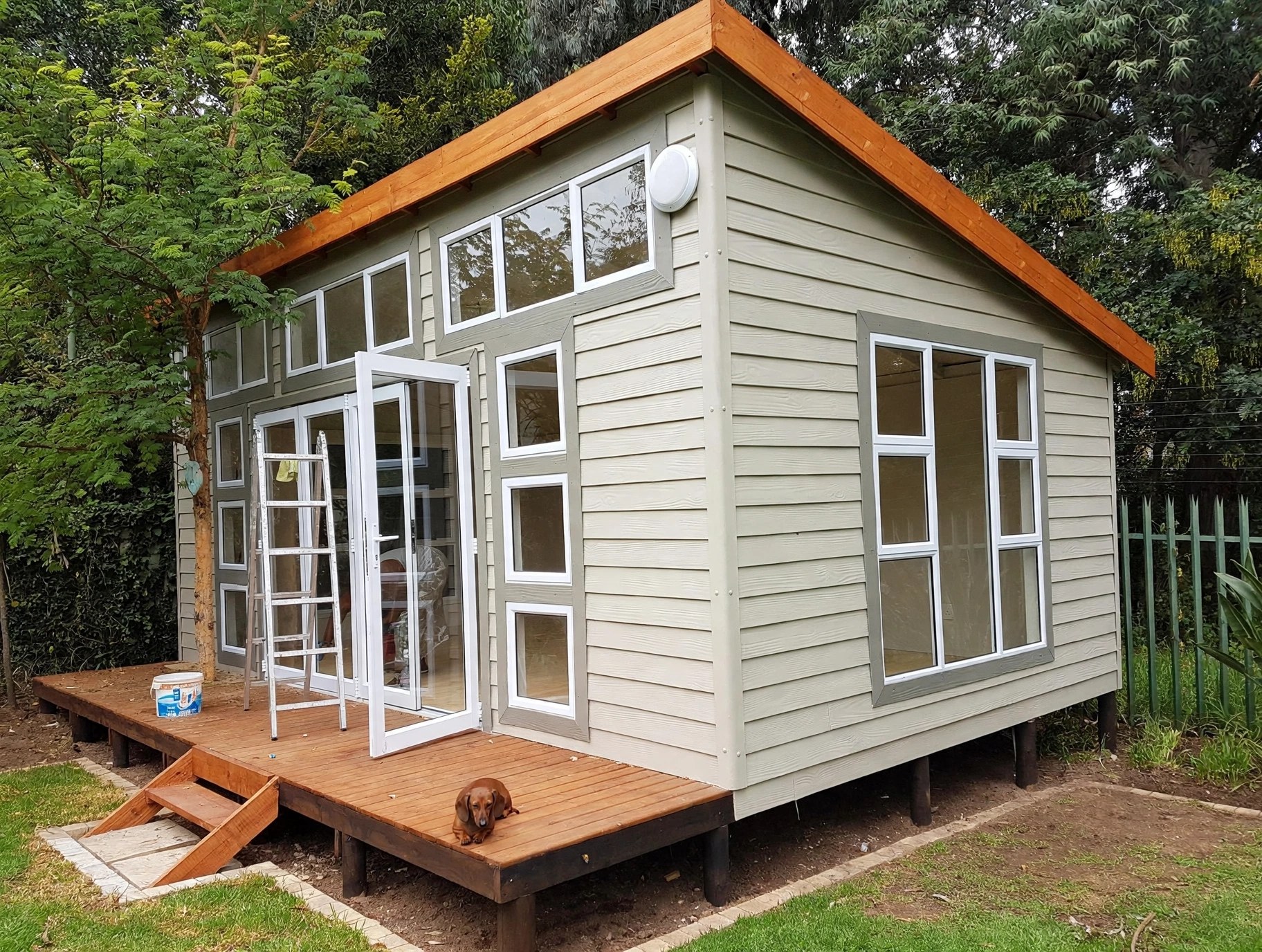 Small grey garden building with tall glazed windows